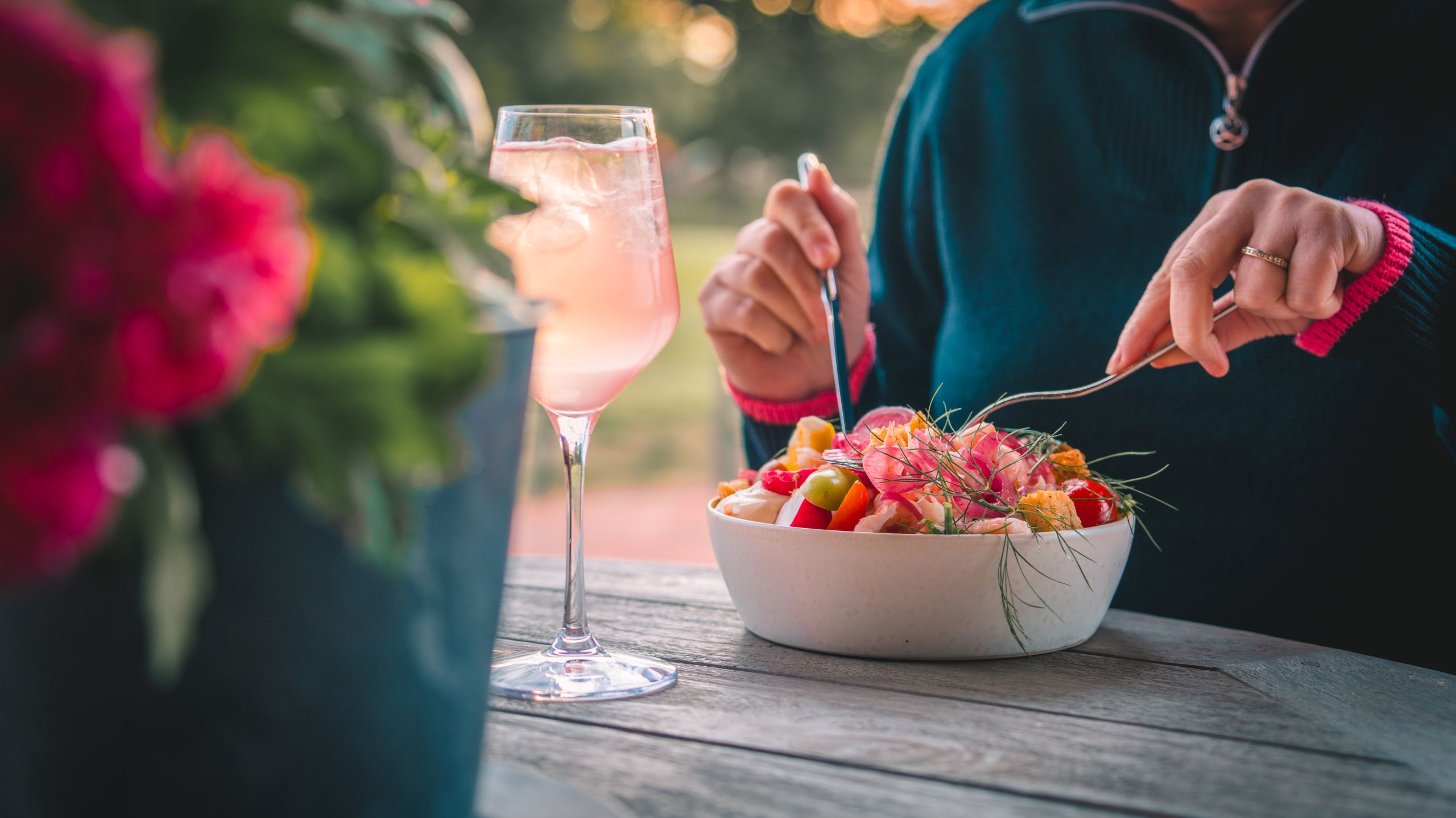 En person sitter och äter en god räksallad i solnedgången.